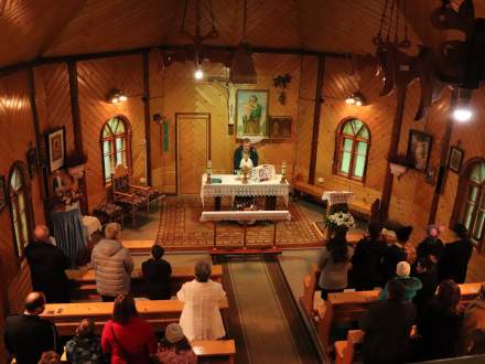Wnętrze kościoła widziane z chóru podczas Mszy Świętej; widoczni zebrani i kapłan odprawiający Mszę Świętą